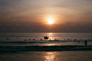 a group of people swimming in the ocean at sunset