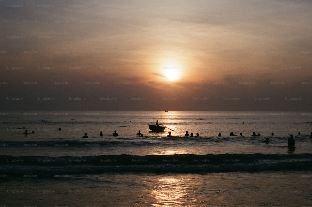 a group of people swimming in the ocean at sunset