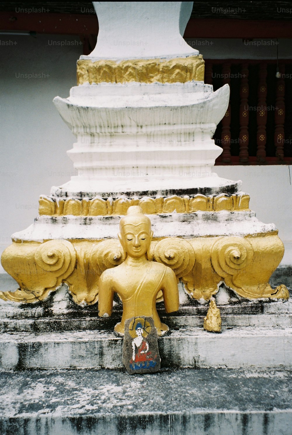 une statue jaune assise au sommet d’une marche en pierre