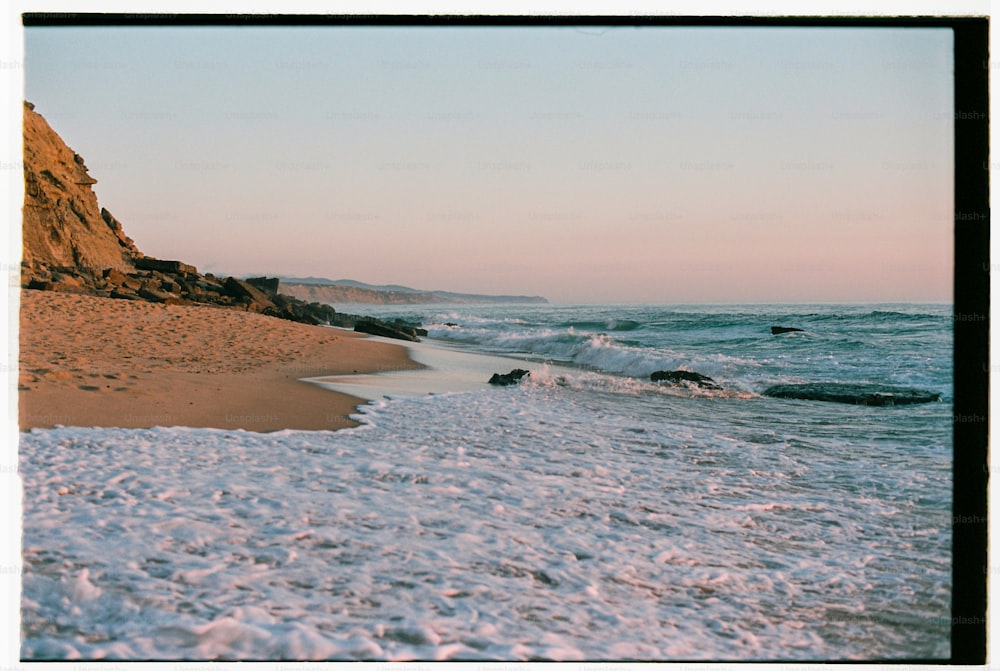 uma praia de areia com ondas chegando à costa