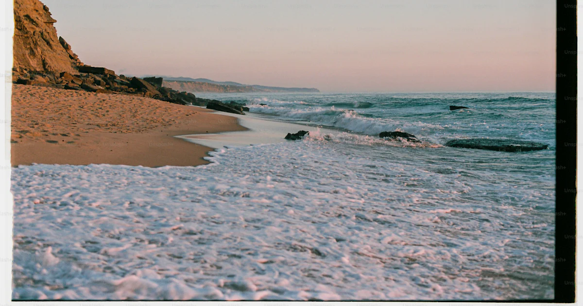 Une plage de sable avec des vagues qui arrivent sur le rivage photo ...