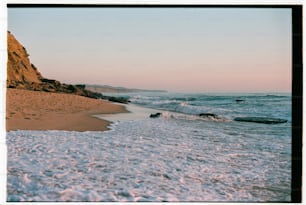 a sandy beach with waves coming in to shore