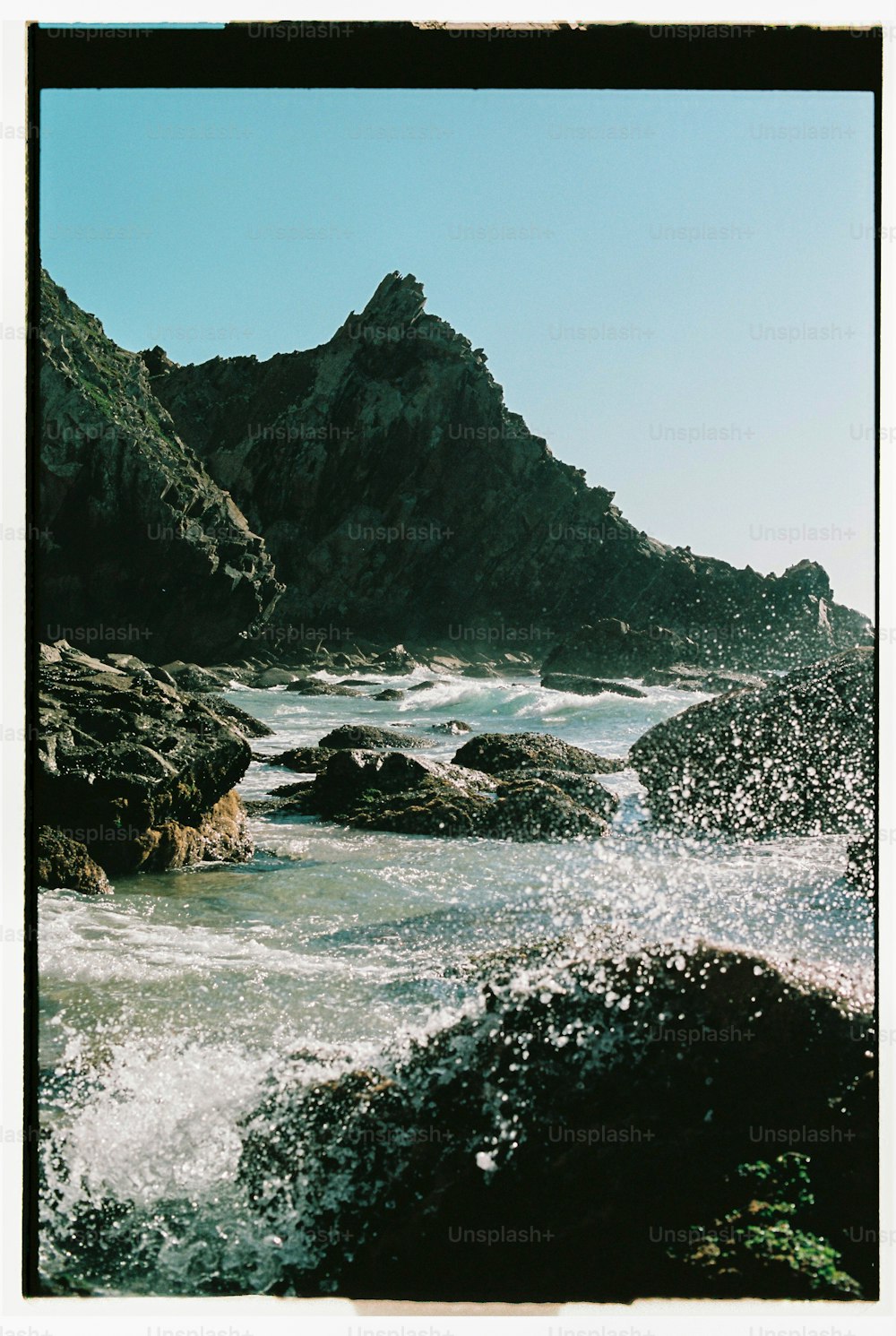 Une photo d’une plage rocheuse avec une planche de surf dans l’eau
