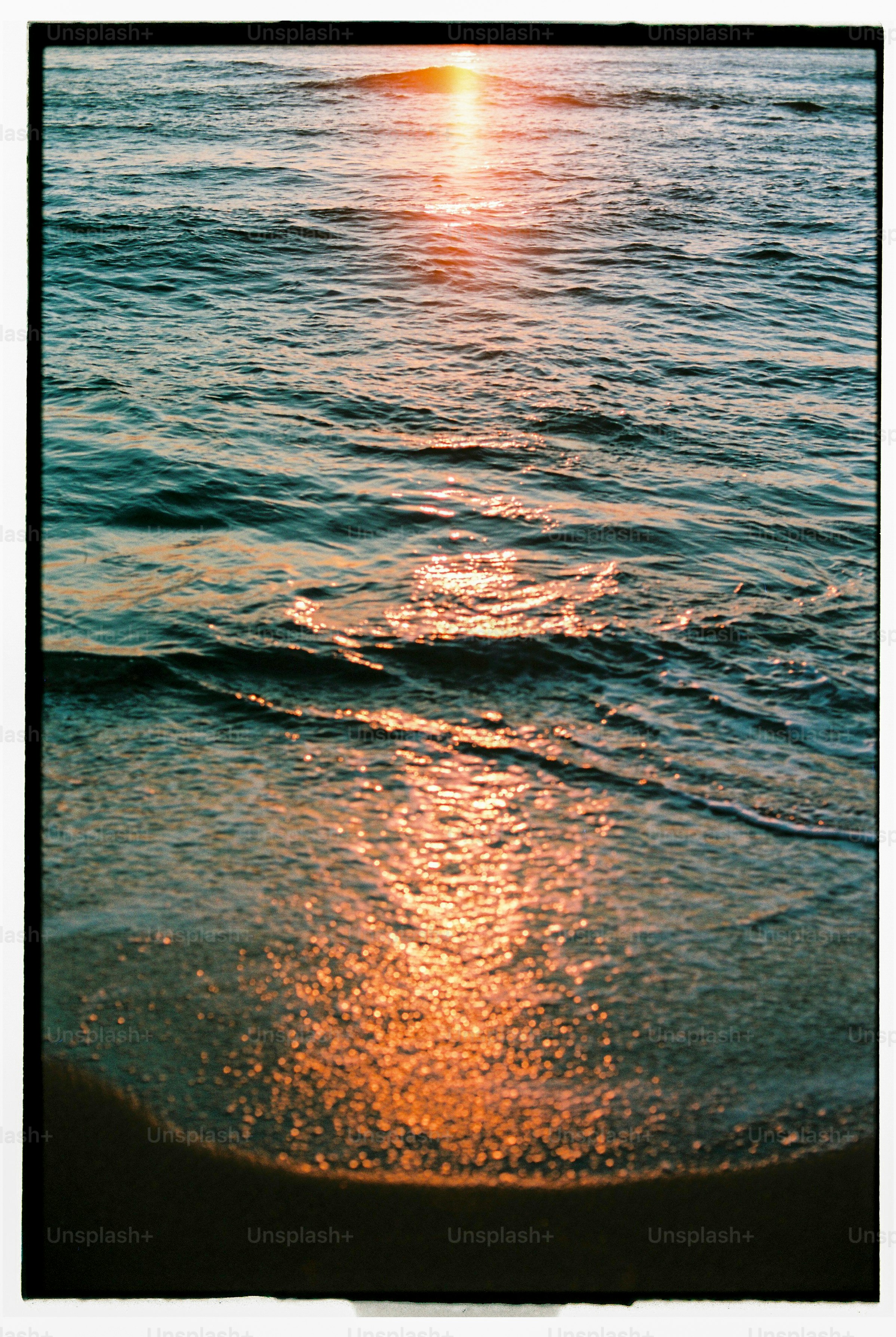 the sun is setting over the water at the beach
