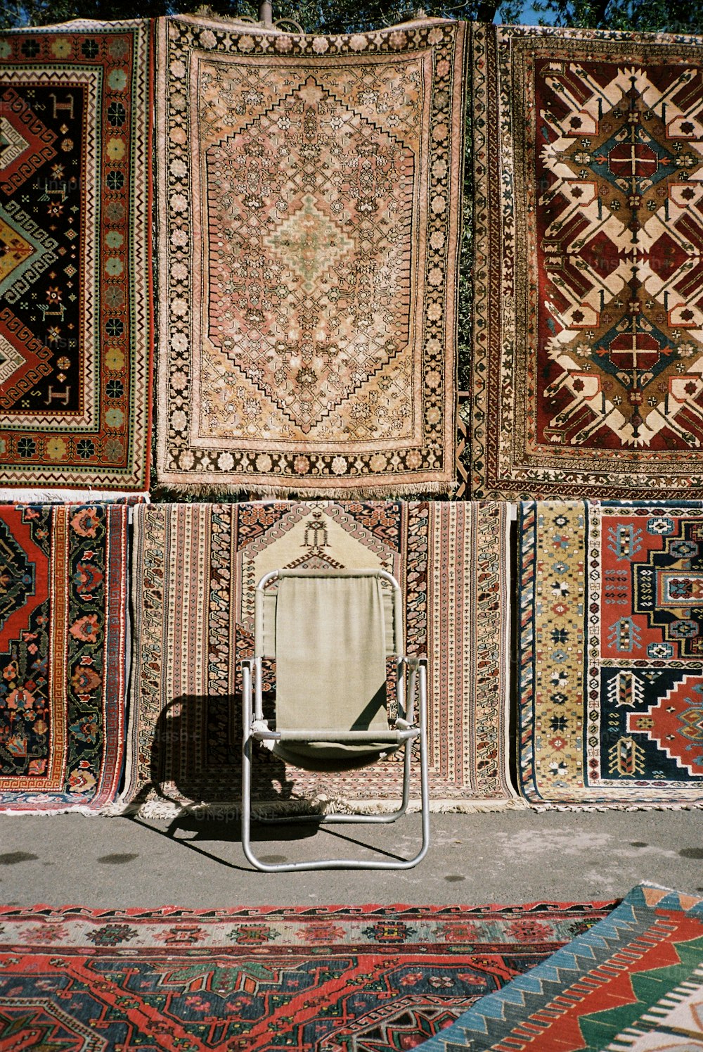 uma cadeira sentada em frente a uma pilha de tapetes