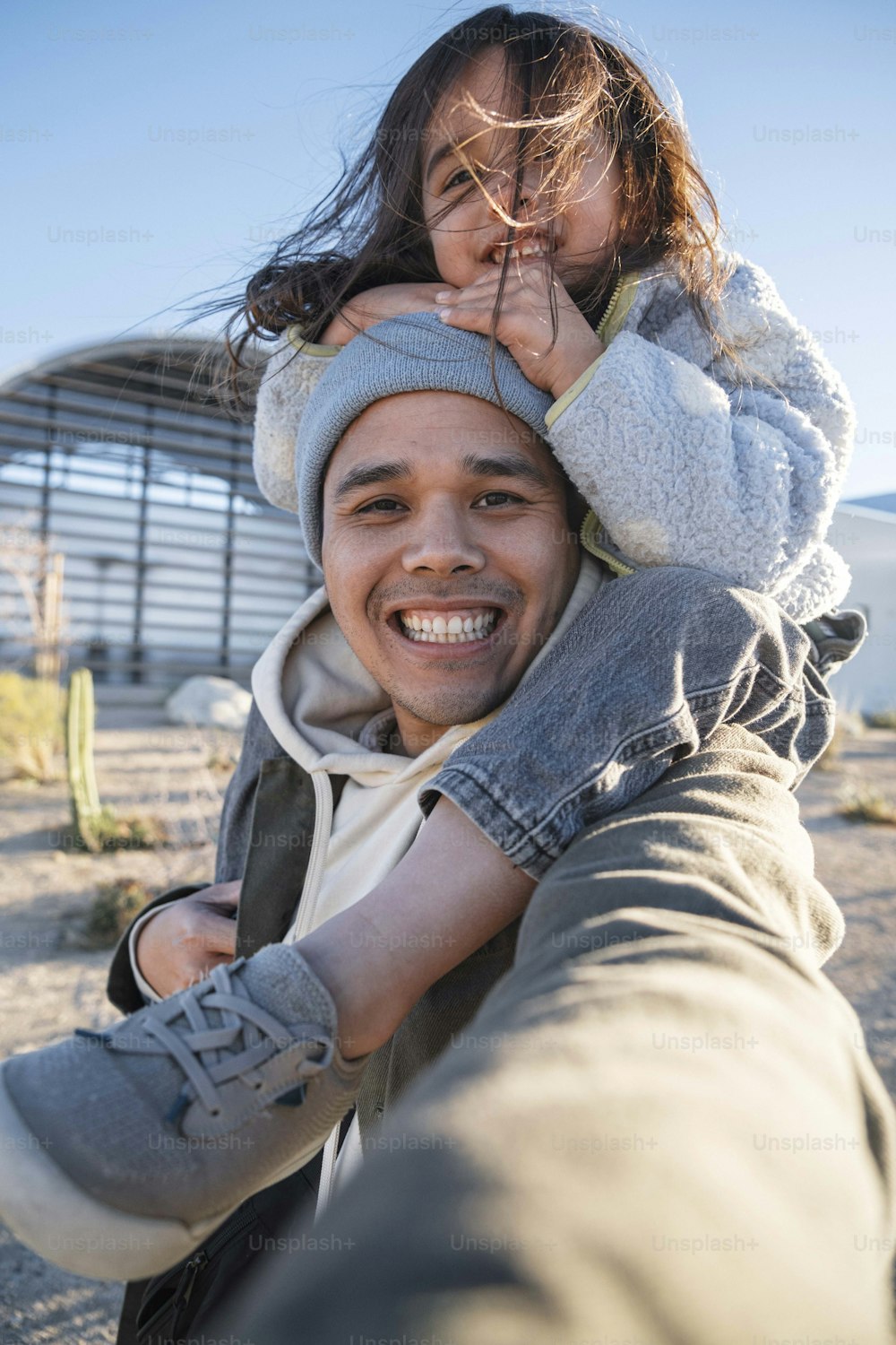 a man holding a little girl on his shoulders