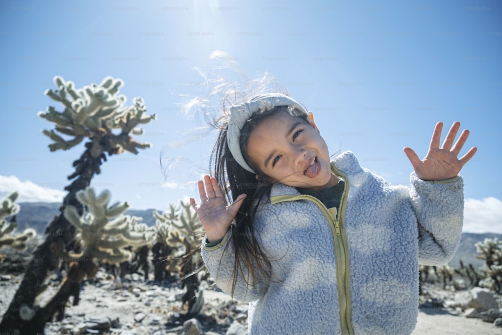 a little girl standing in front of a cactus