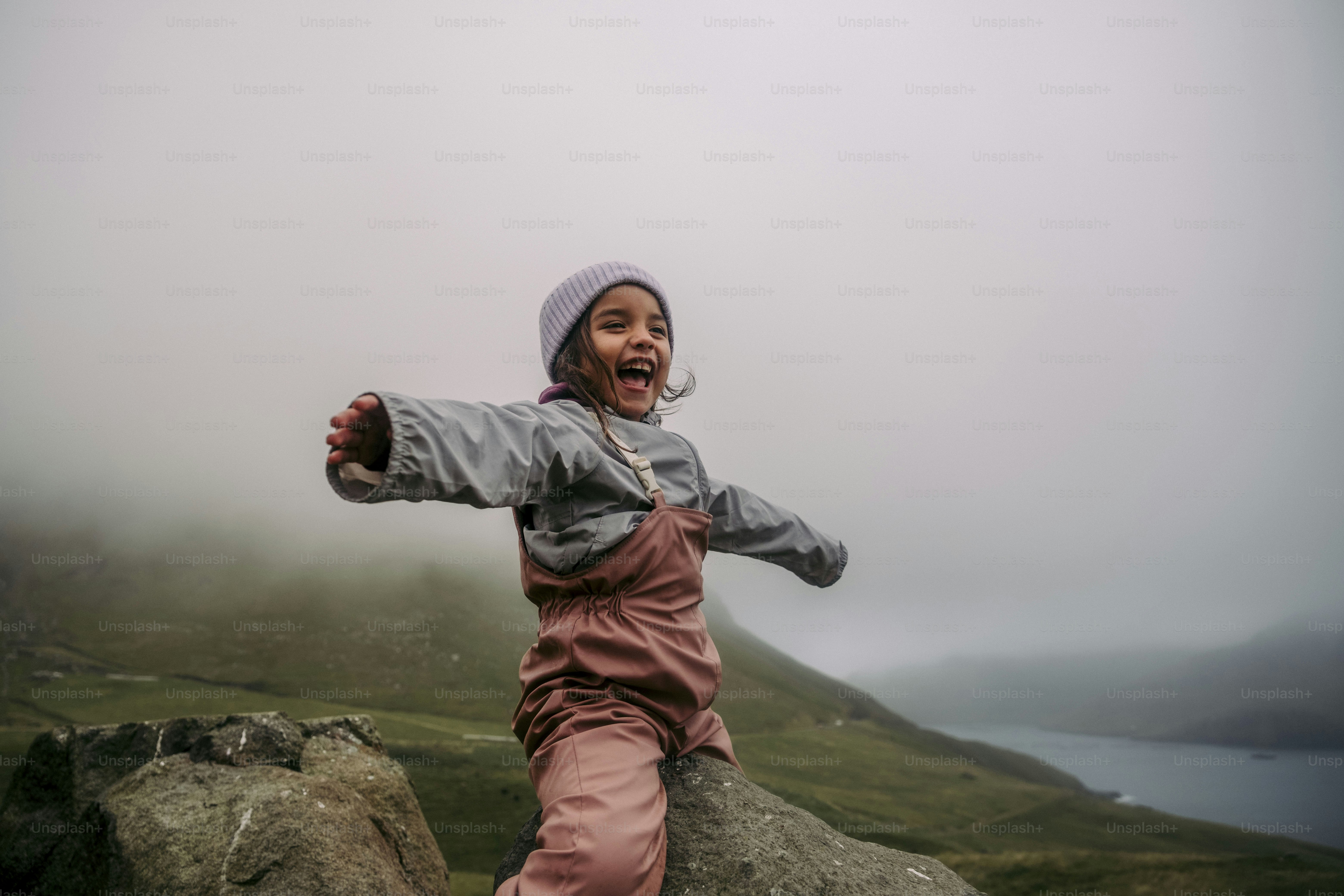 a young girl standing on top of a large rock