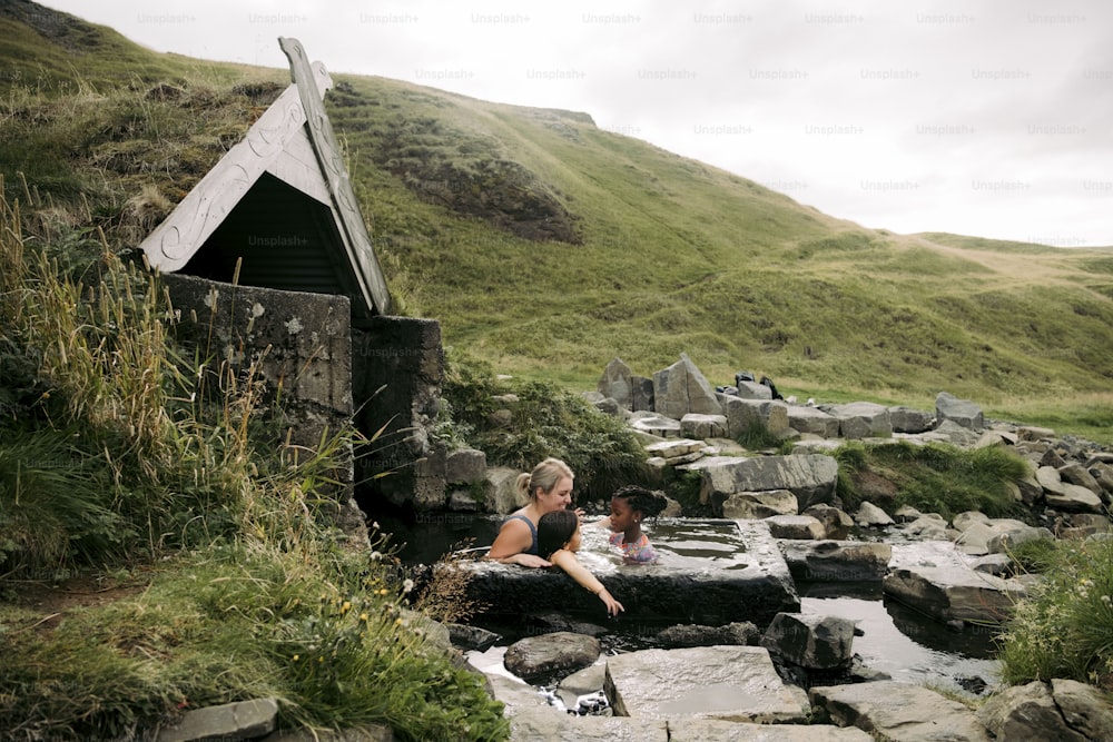 a woman and a child sitting on rocks near a stream