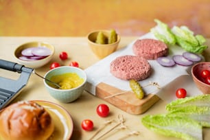a cutting board topped with hamburgers and vegetables