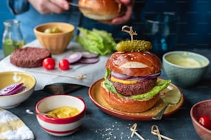 um hambúrguer sentado em cima de um prato ao lado de tigelas de comida