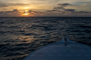 the sun is setting over the ocean as seen from a boat