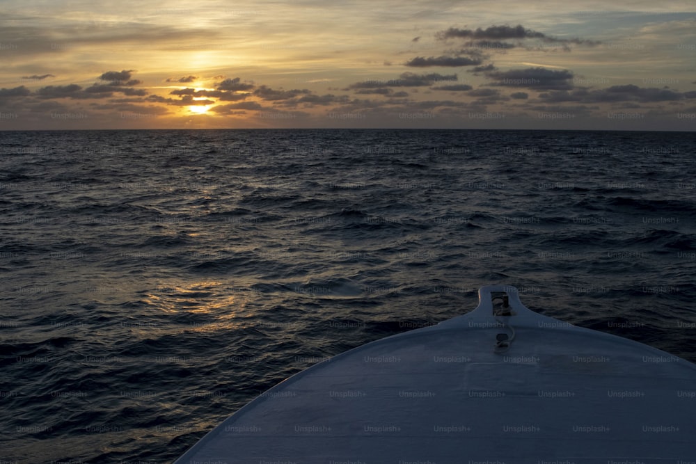 the sun is setting over the ocean as seen from a boat