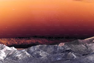 a view of a mountain range with a red sky in the background