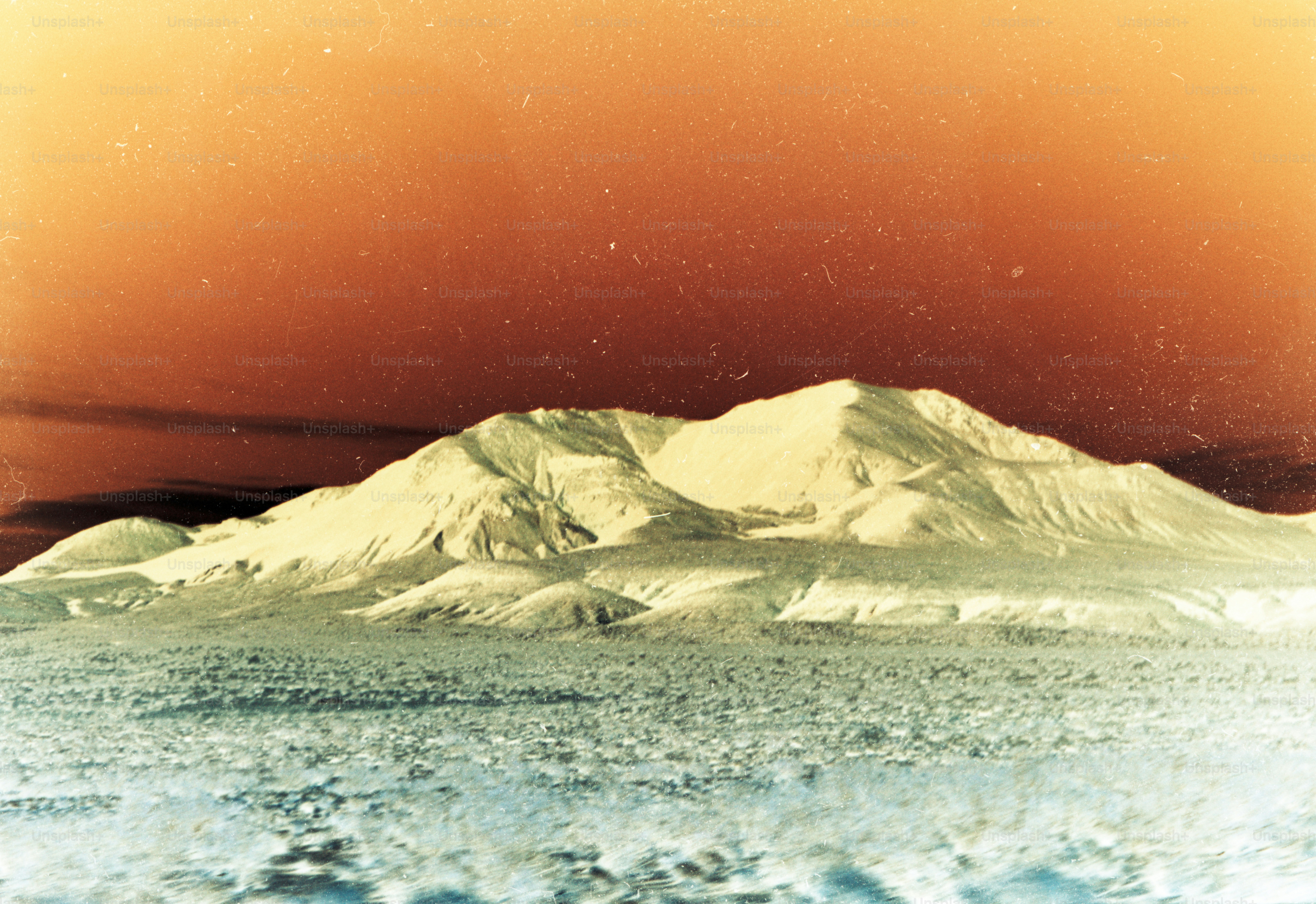 a picture of a snow covered mountain under a red sky
