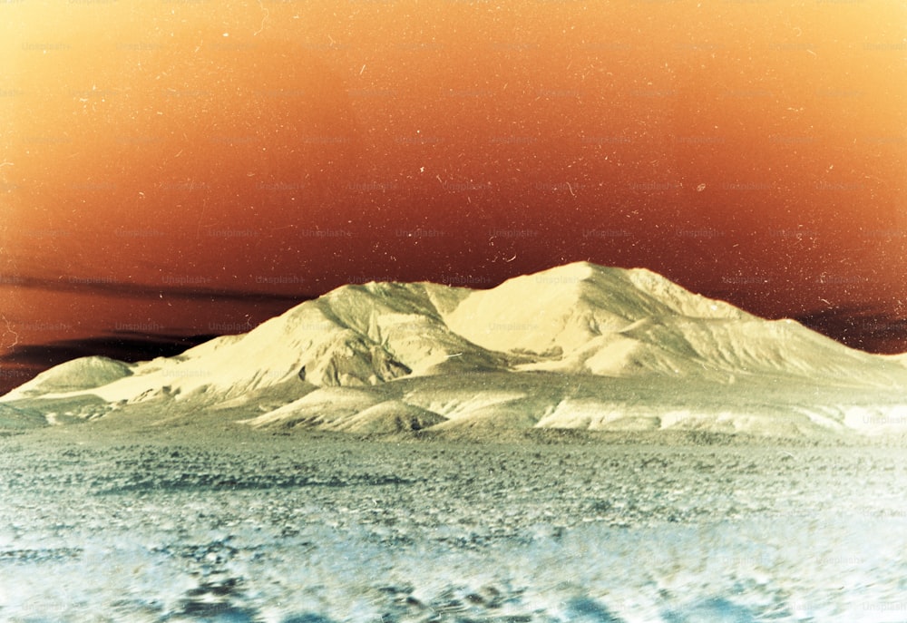 a picture of a snow covered mountain under a red sky