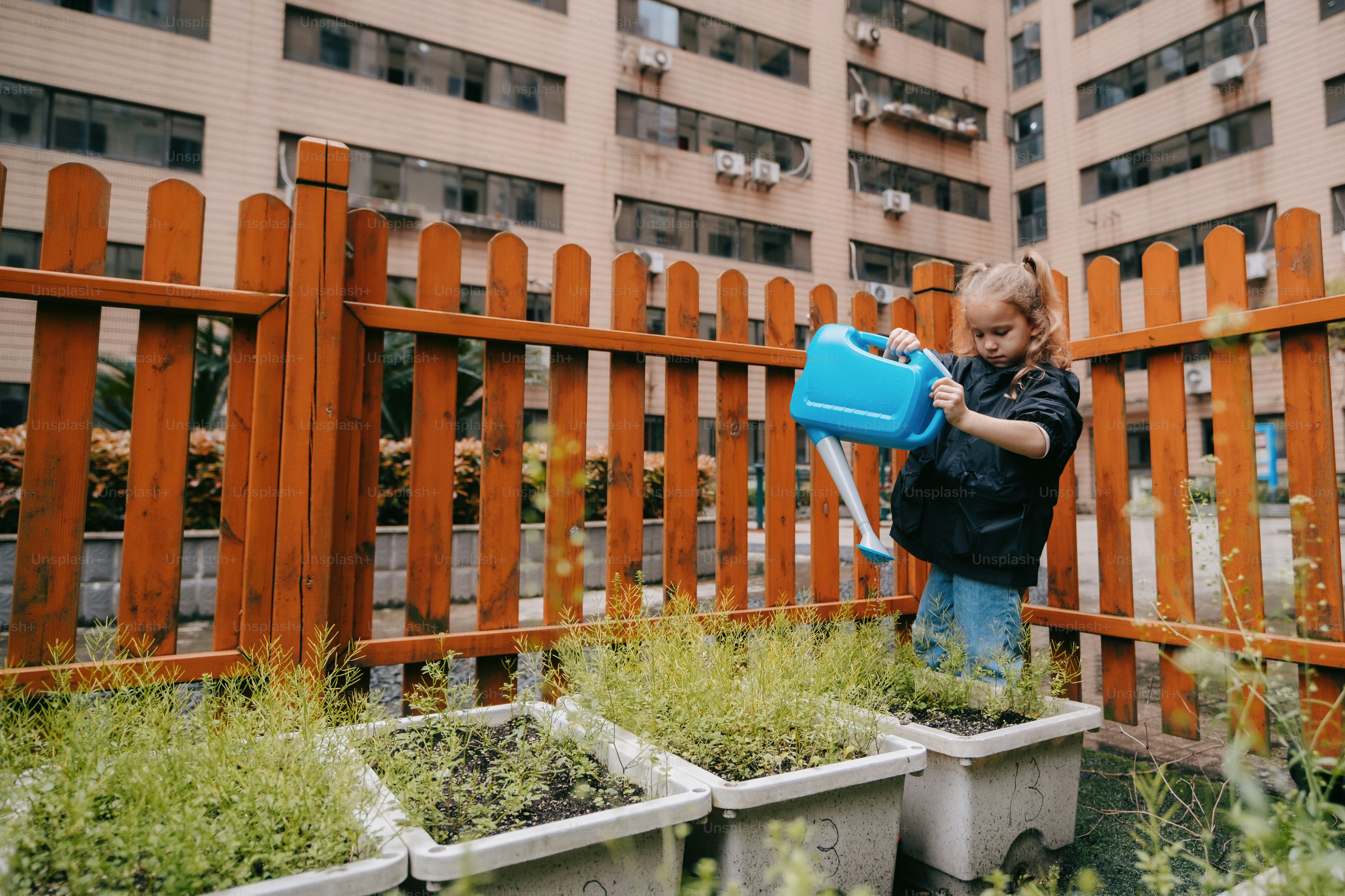 a little girl holding a blue watering can