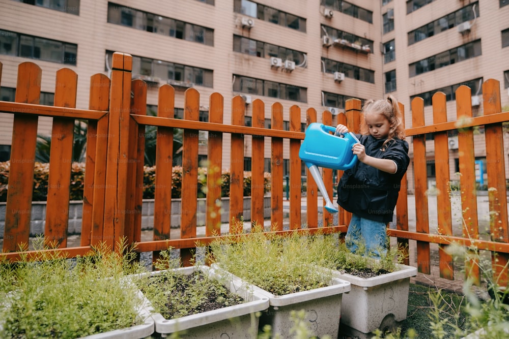 a little girl holding a blue watering can