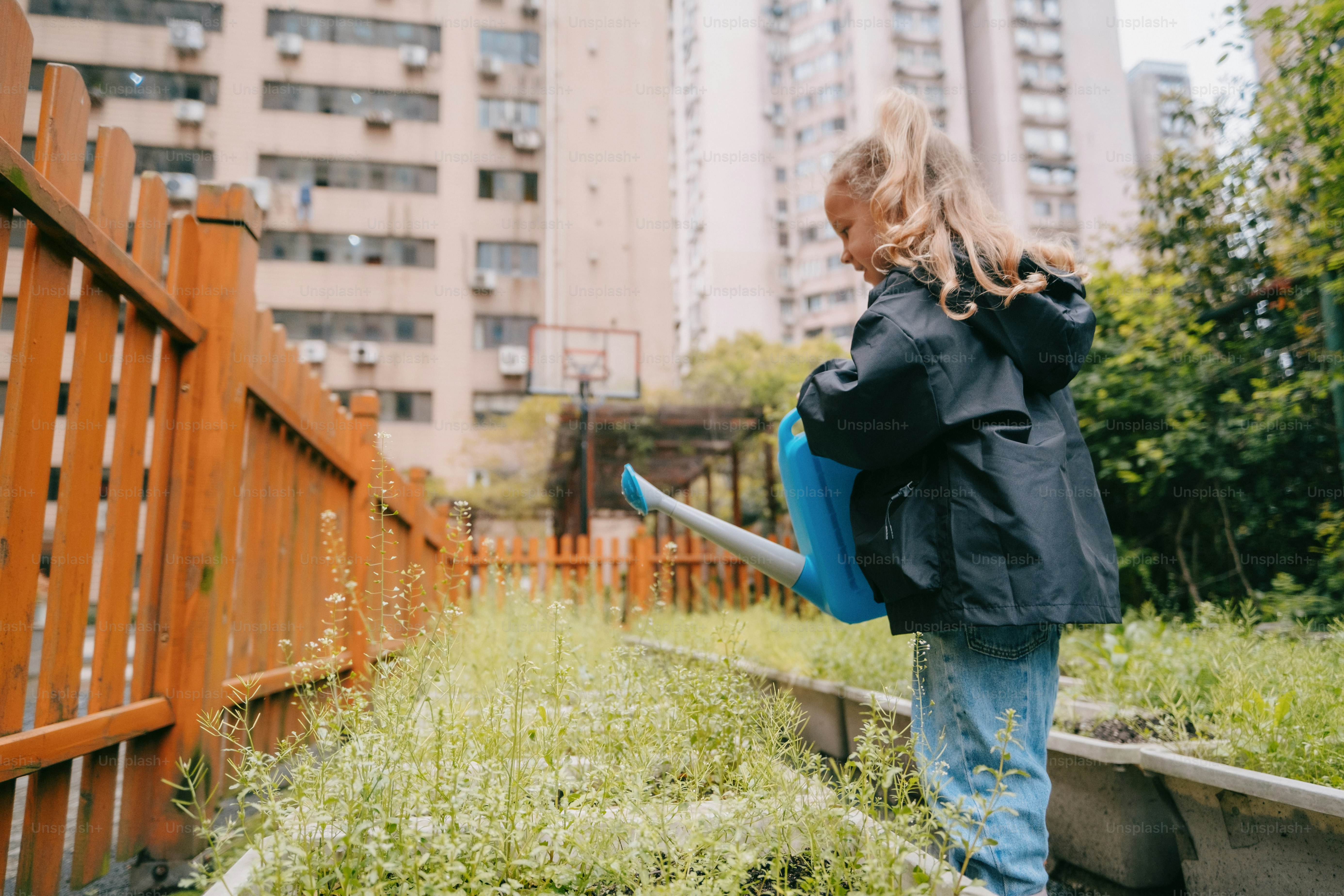 a little girl holding a blue watering hose