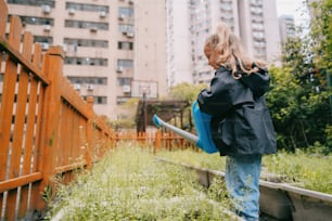 a little girl holding a blue watering hose