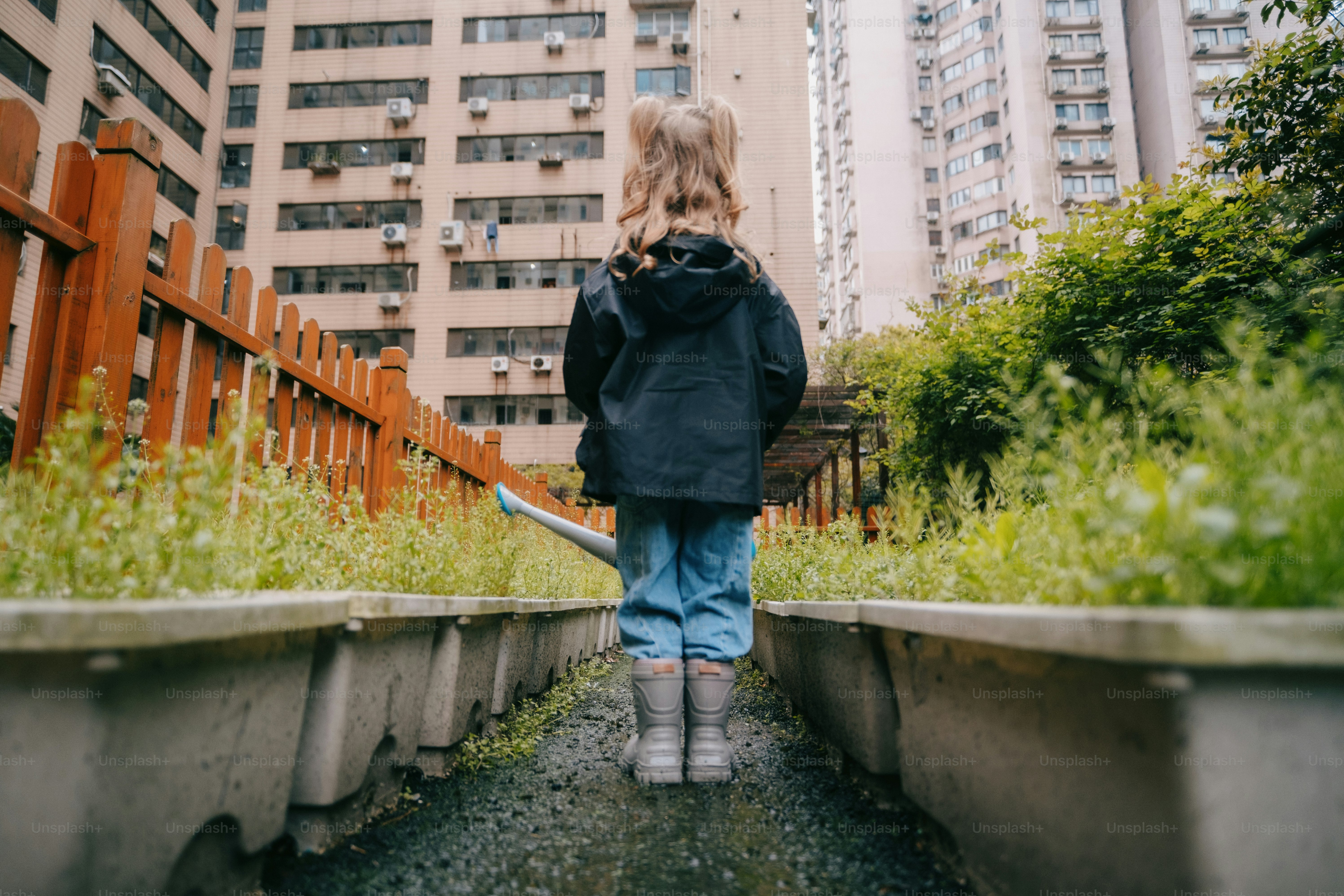 a little girl walking down a path in a city