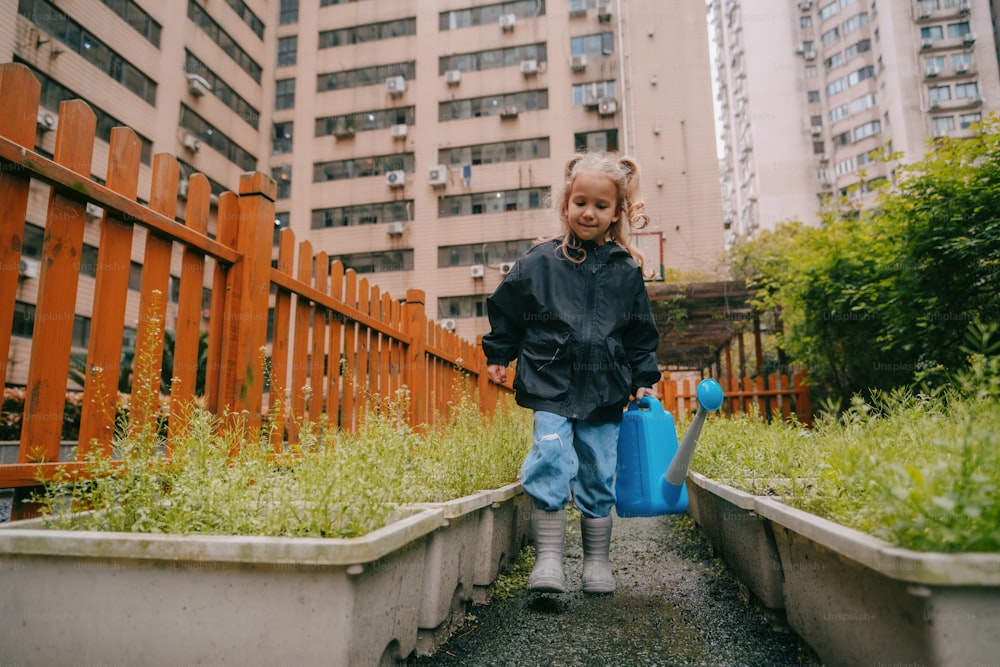 a young girl carrying a blue suitcase down a path