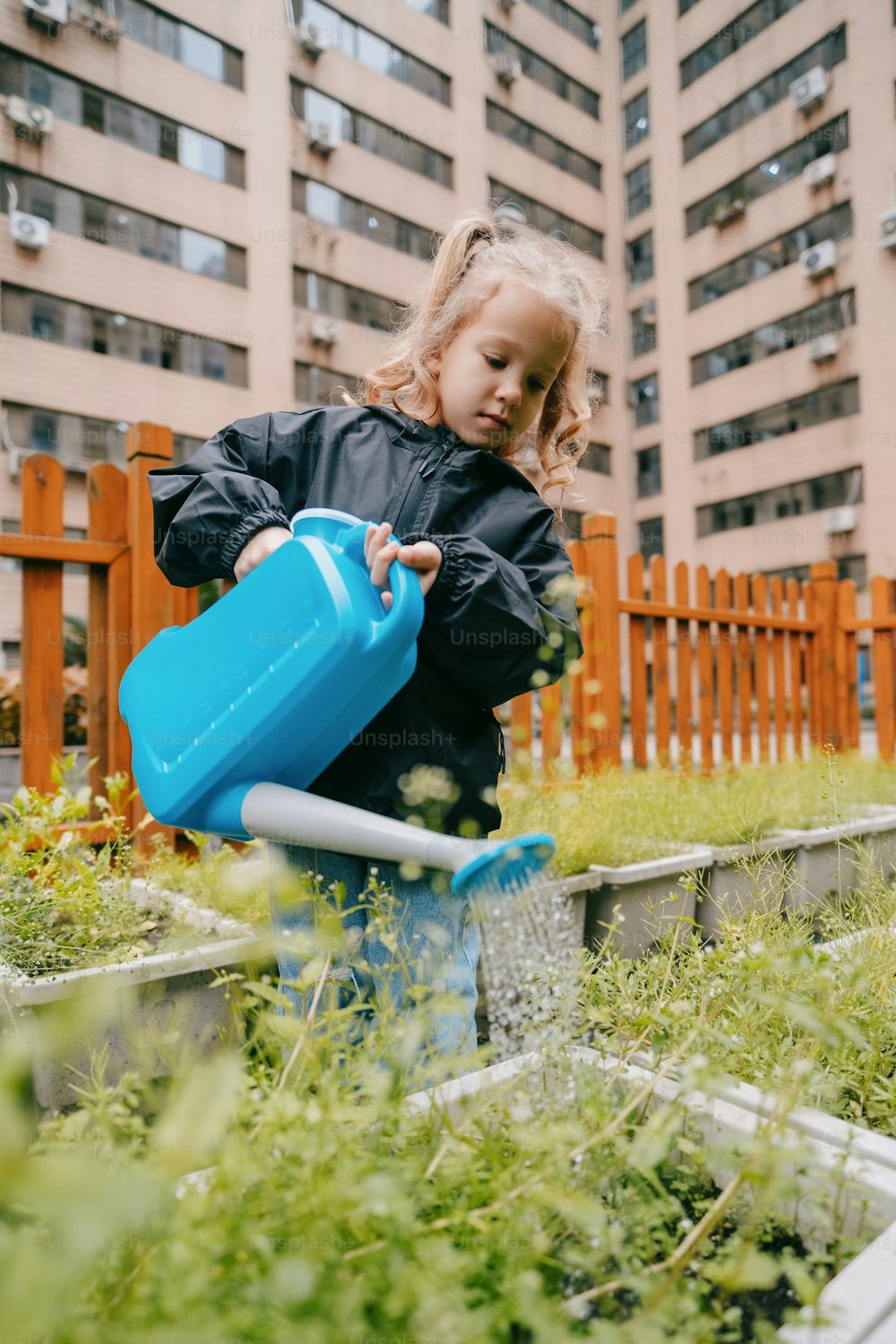 파란 물뿌리개로 정원에 물을 주는 어린 소녀