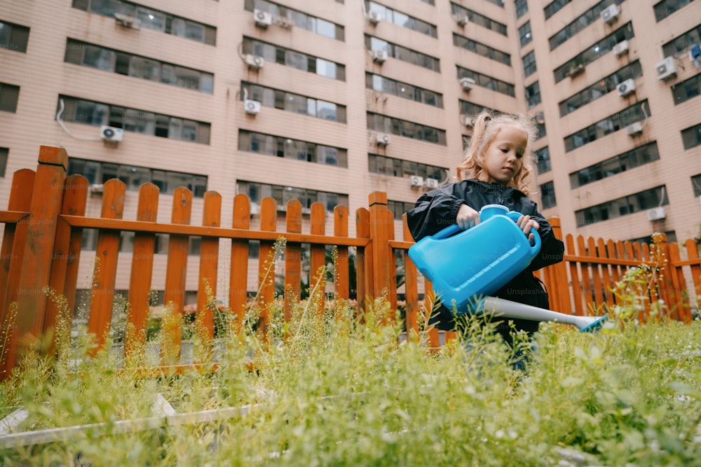 a little girl holding a blue watering can