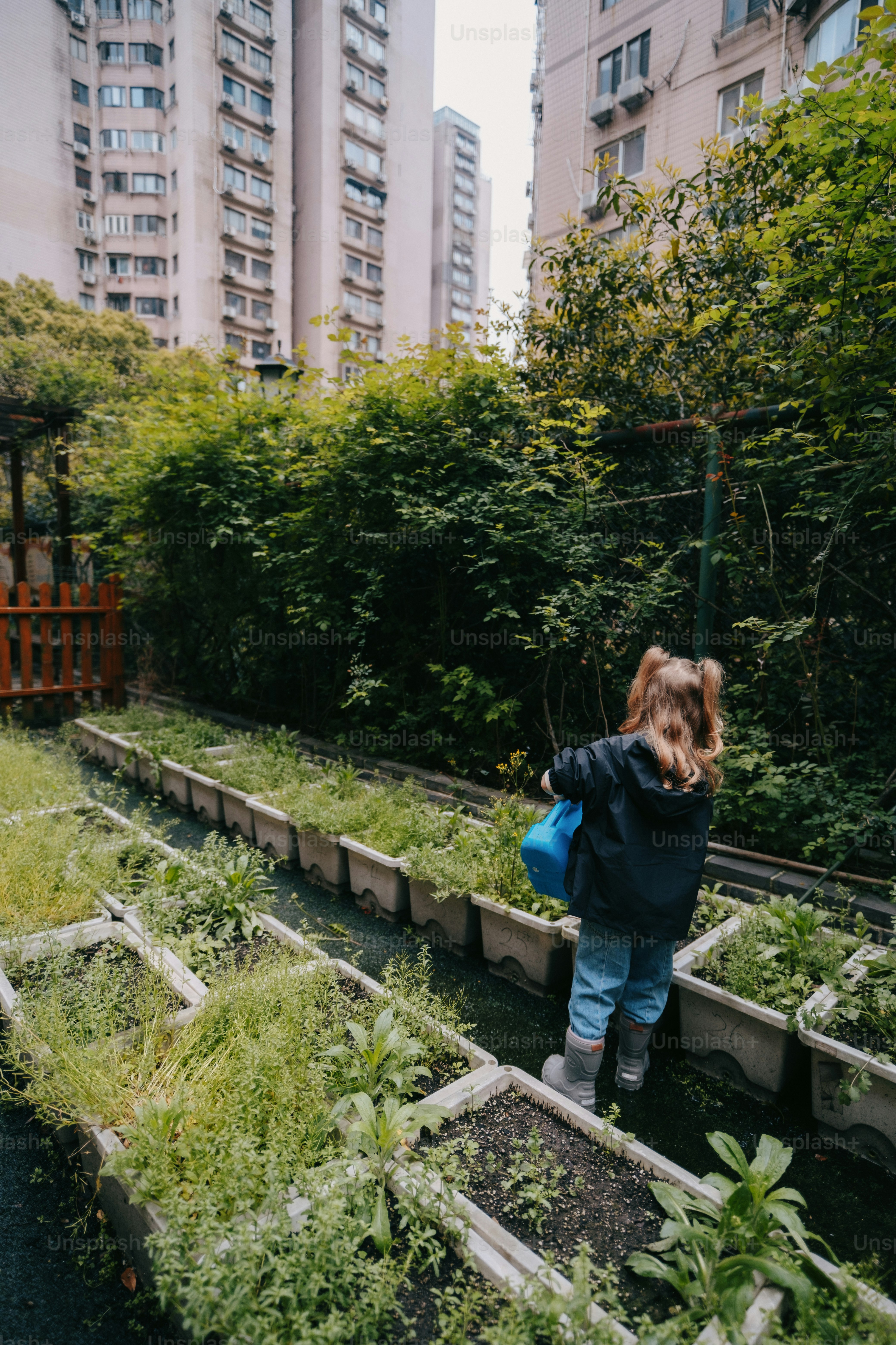 a little girl standing in a garden filled with lots of plants