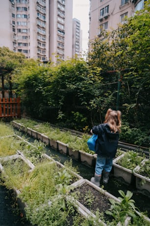 a little girl standing in a garden filled with lots of plants
