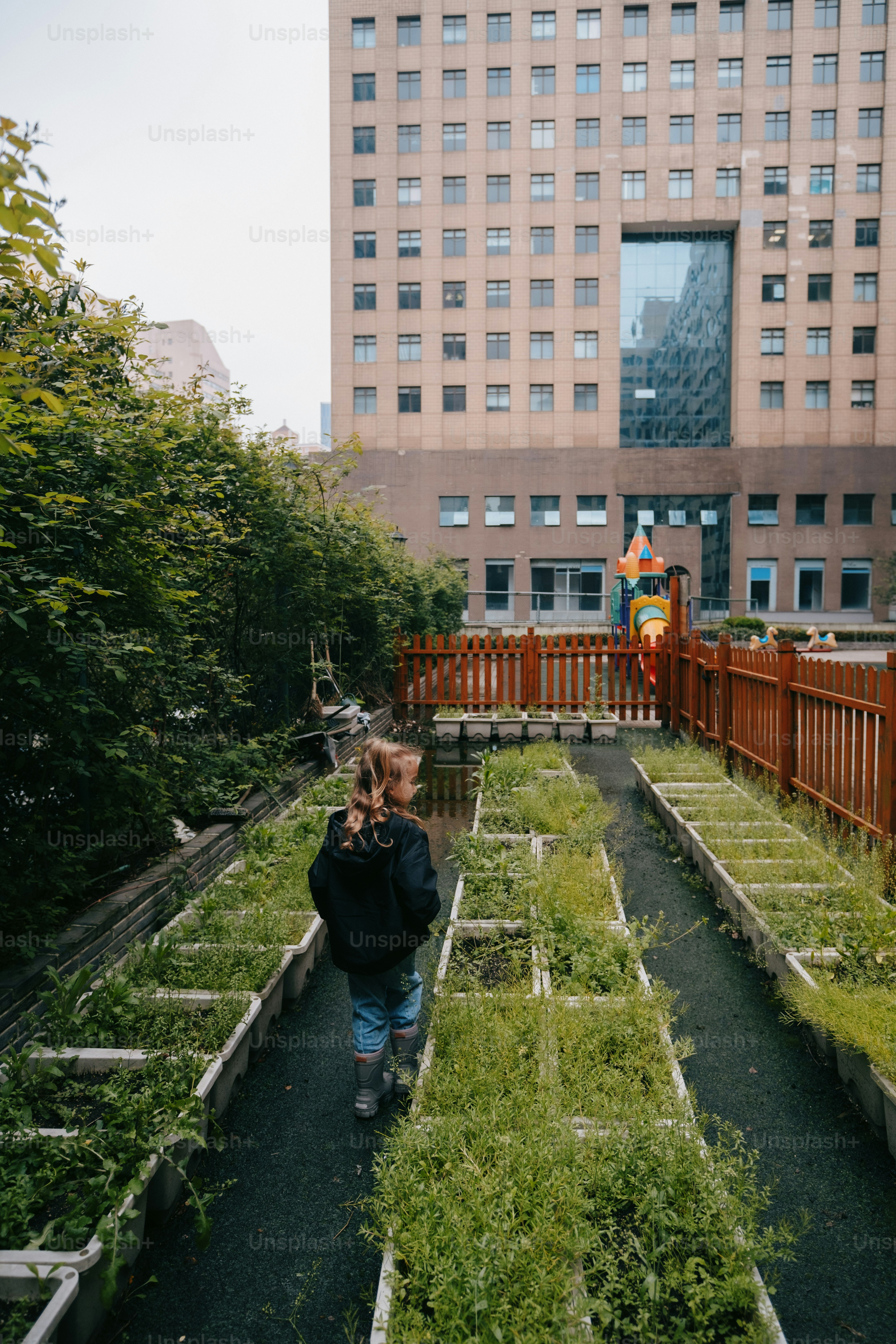 a young child walking through a garden in front of a tall building
