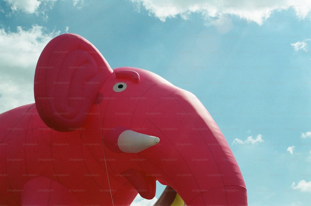 a large red elephant balloon flying in the sky
