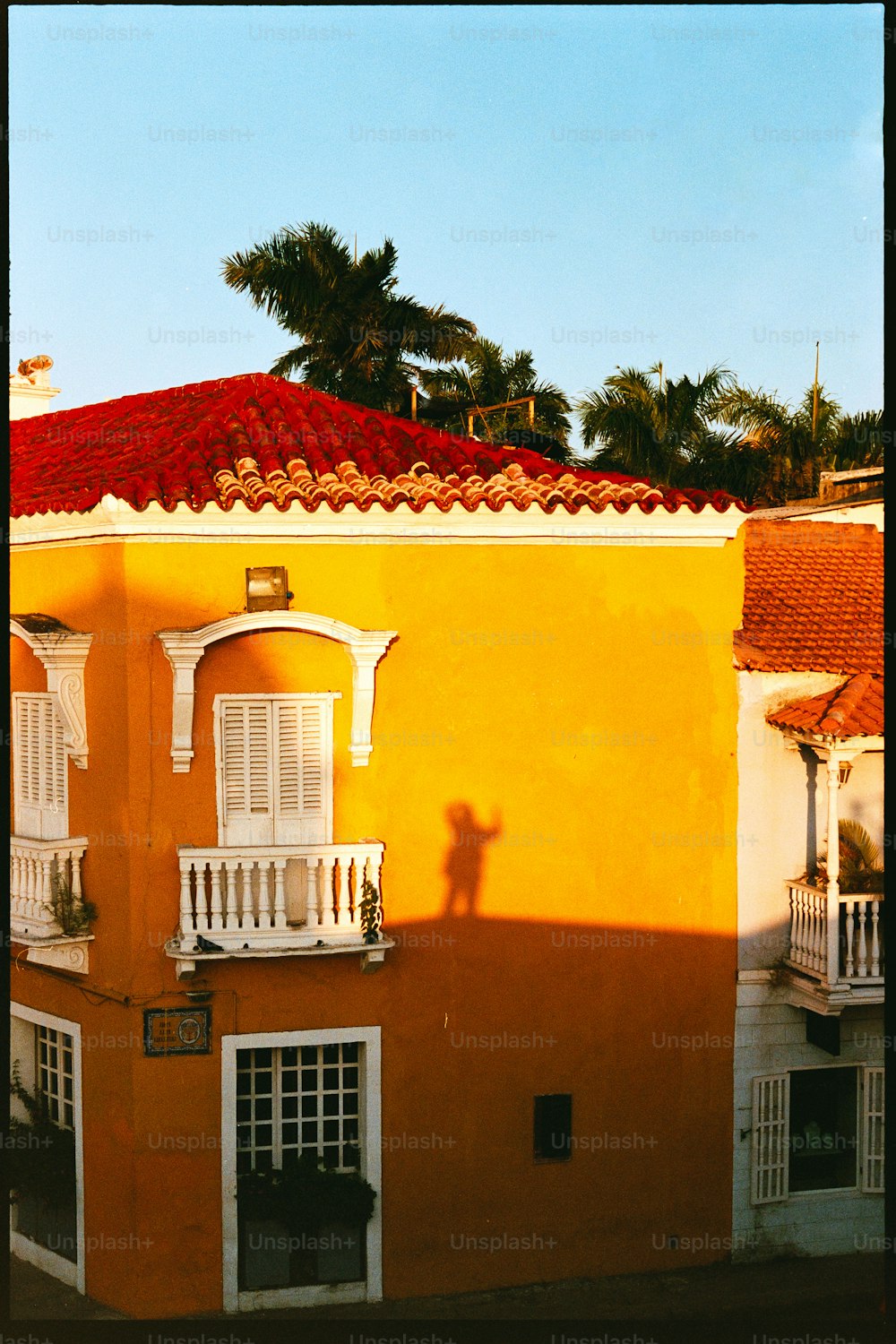 a yellow building with white balconies and a red roof