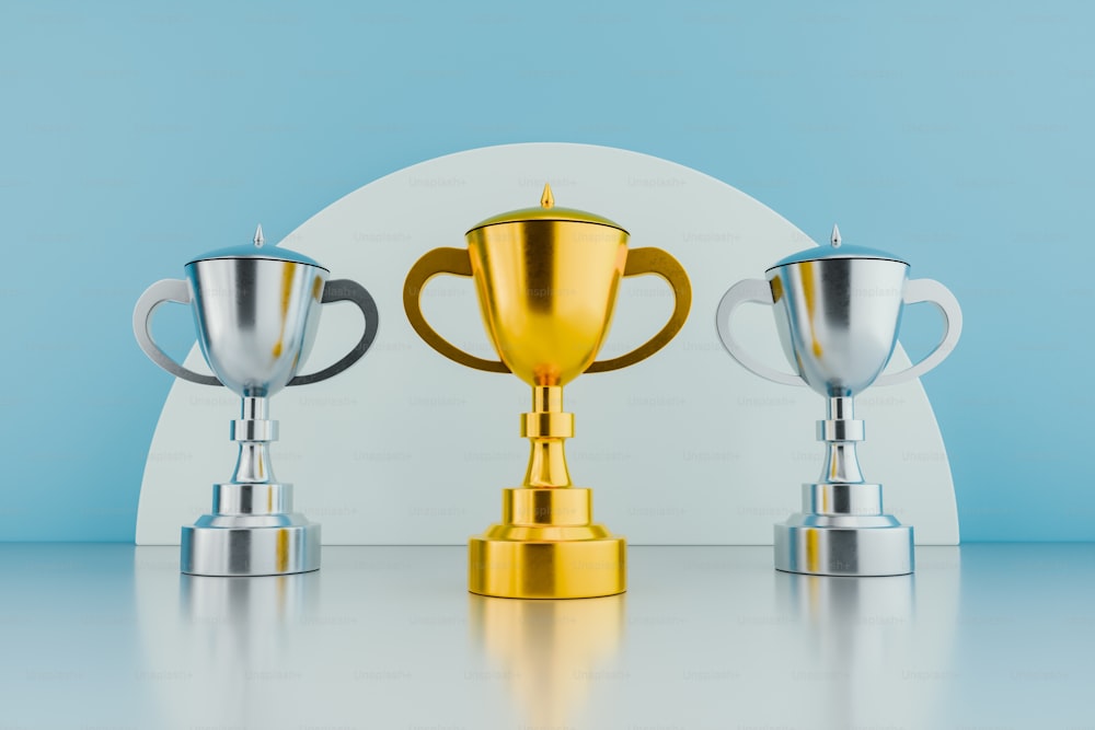 three silver and gold trophies on a table