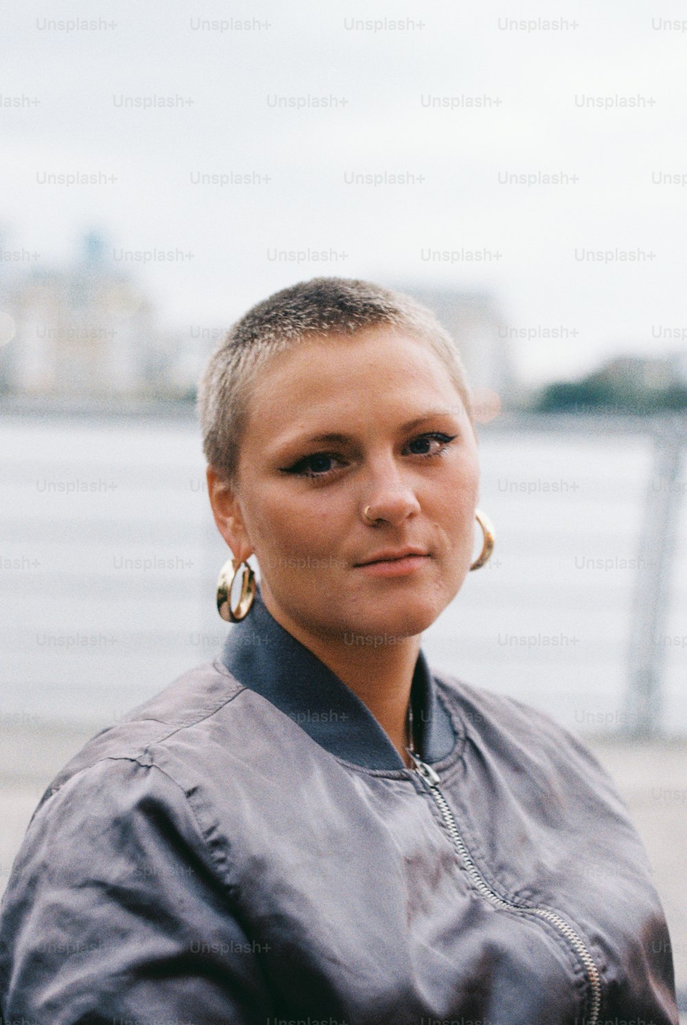 a woman with large hoop earrings standing by the water