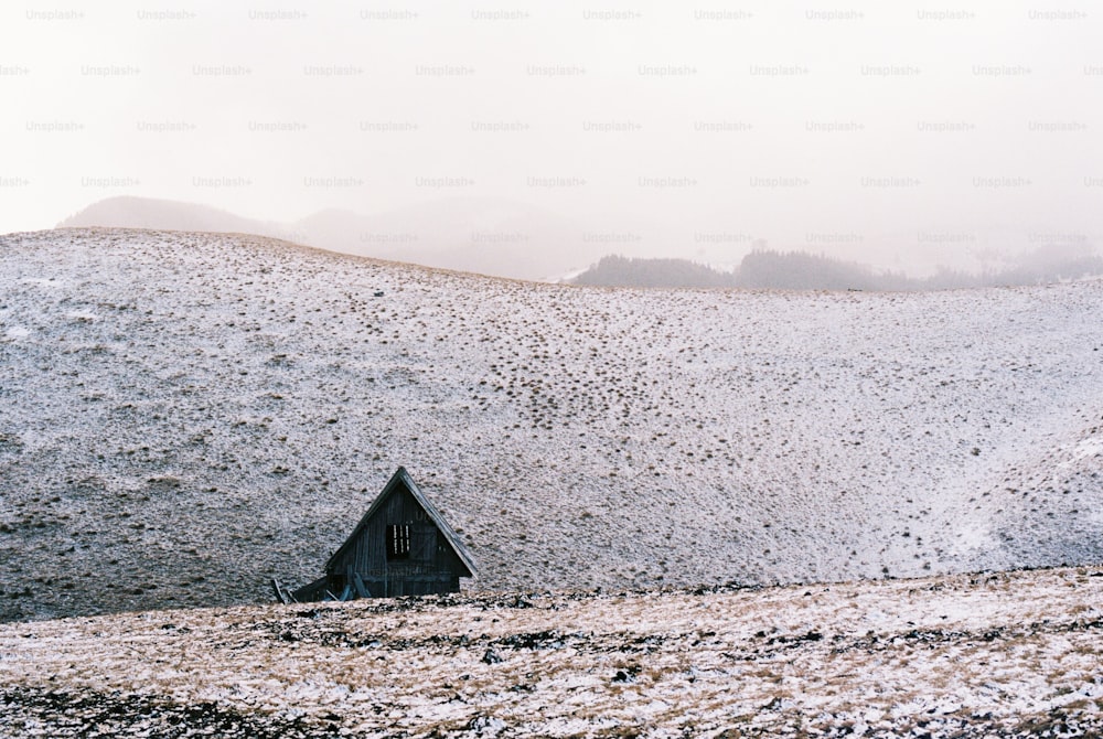 uma colina coberta de neve com uma casa em cima dela