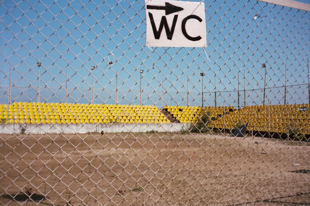 Ein Schild an einem Maschendrahtzaun mit der Aufschrift W C