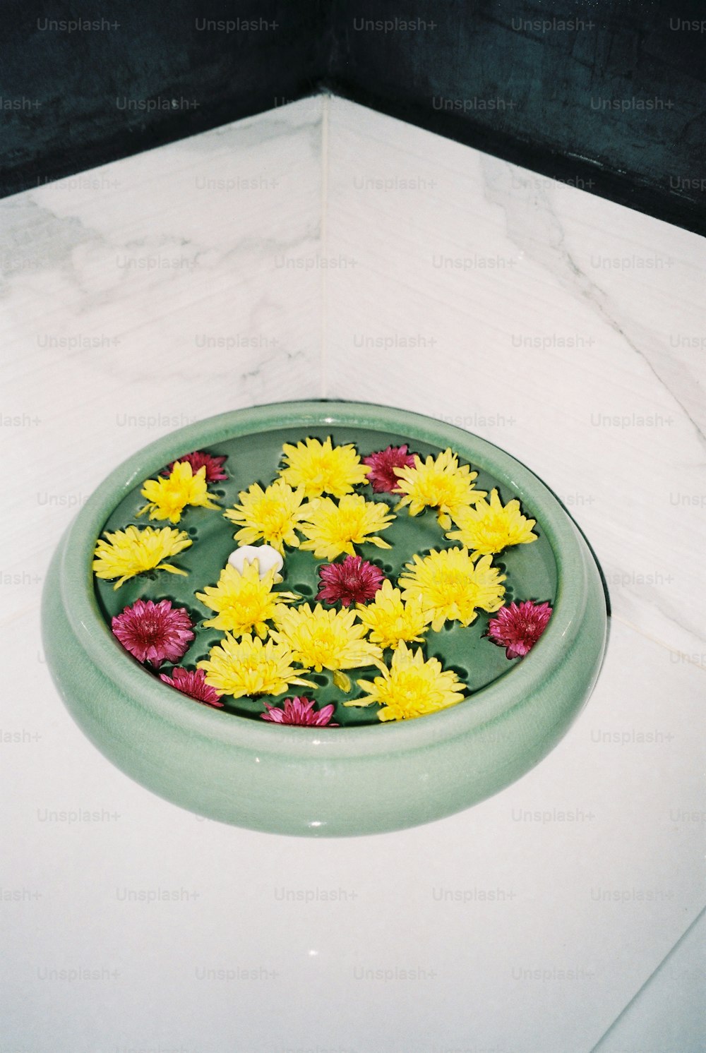 a green bowl filled with yellow and red flowers