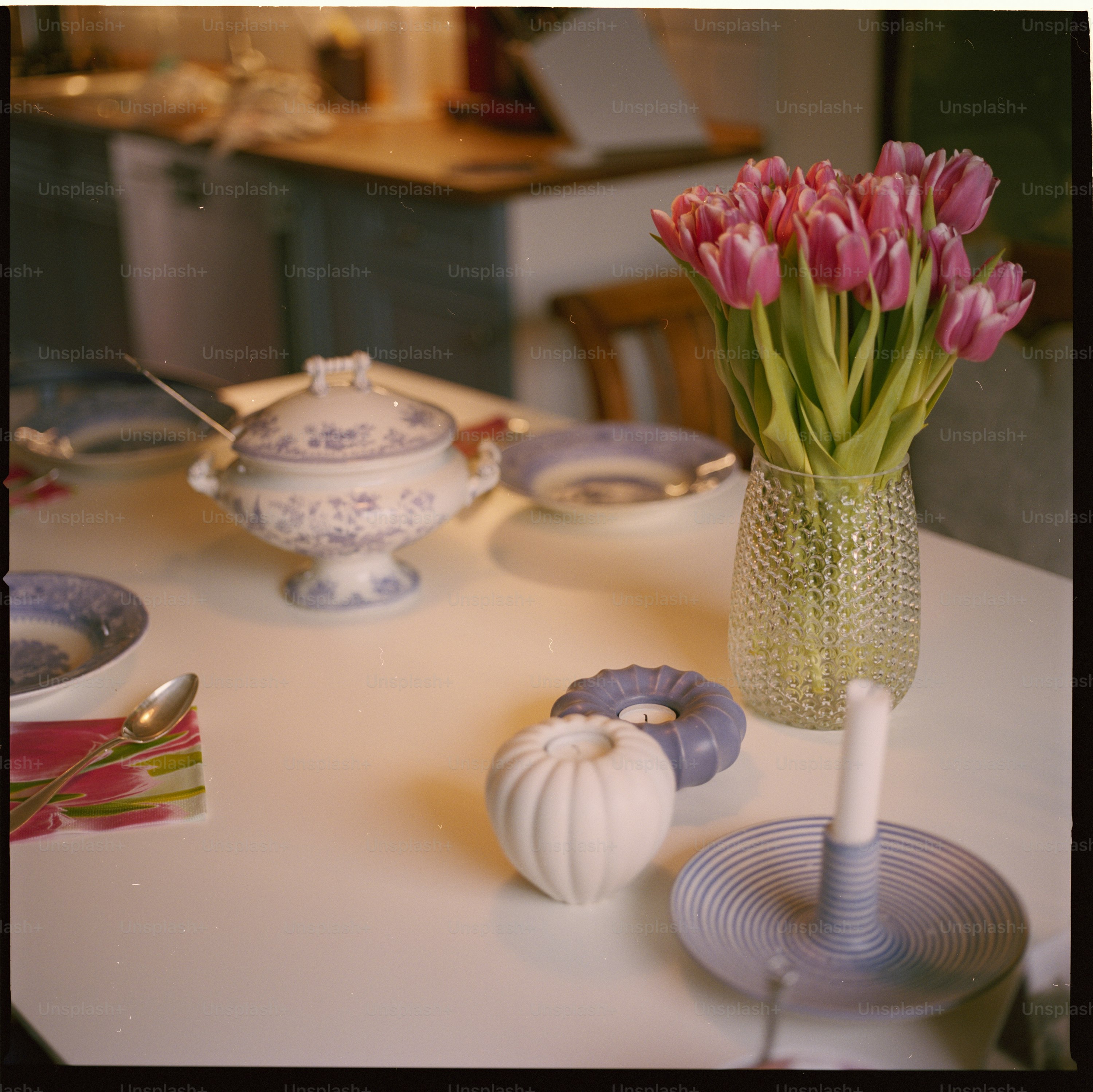 une table blanche surmontée d’un vase rempli de fleurs roses