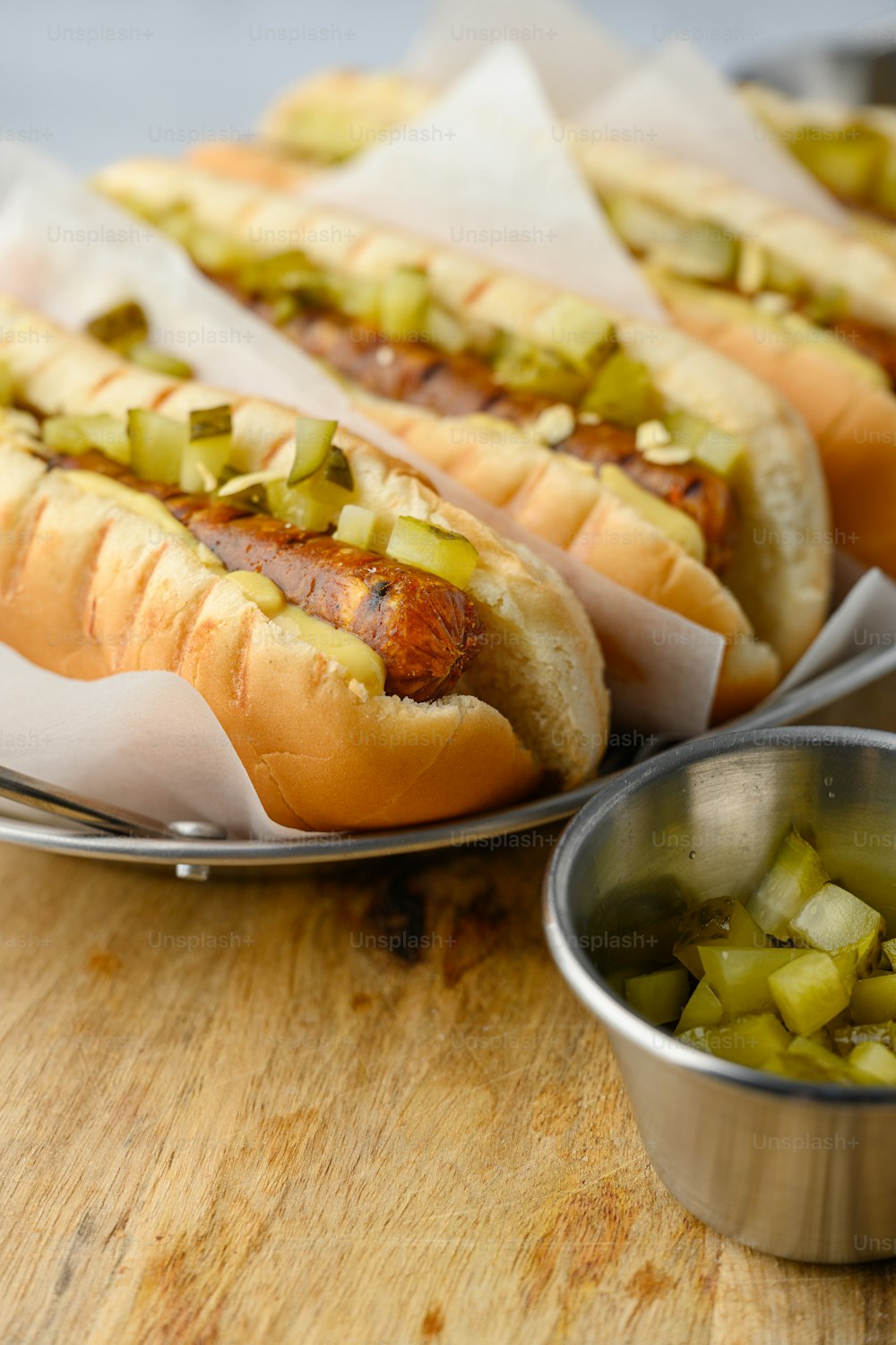three hot dogs with pickles and mustard on a plate