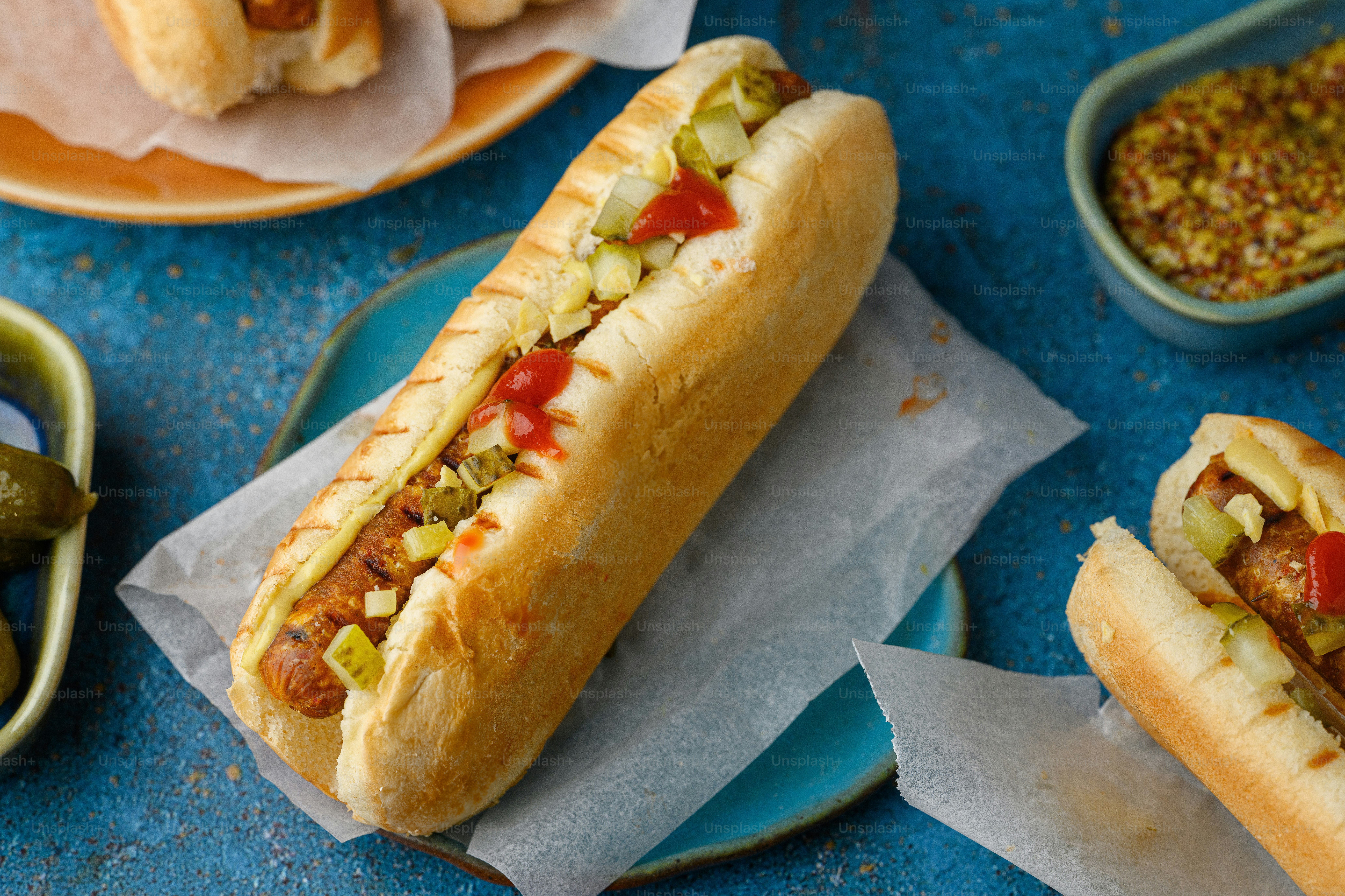 two hot dogs on buns with toppings on plates