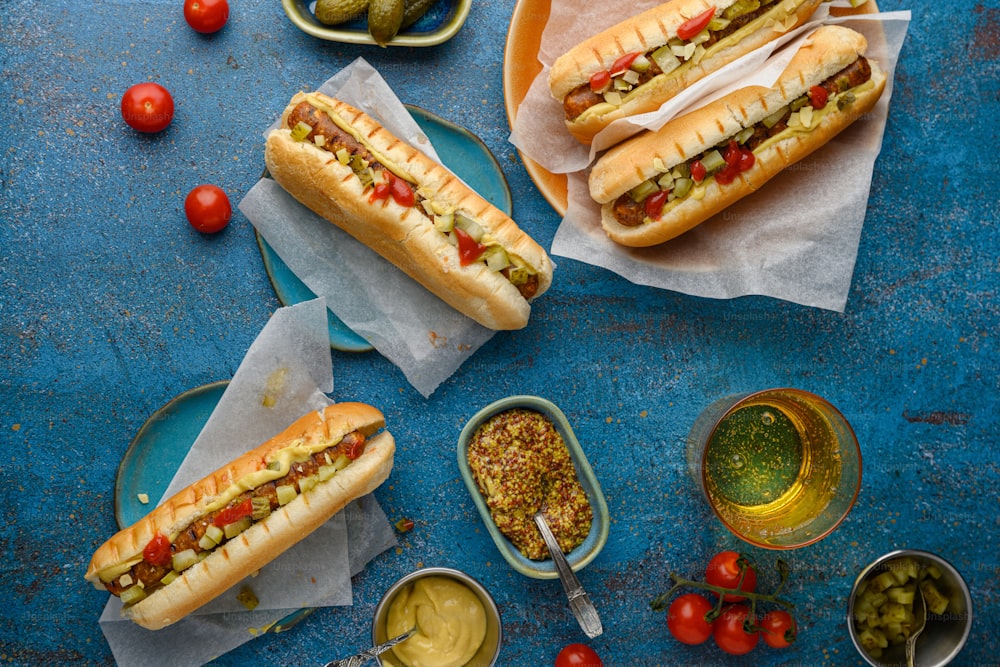 two hot dogs on buns with pickles and tomatoes