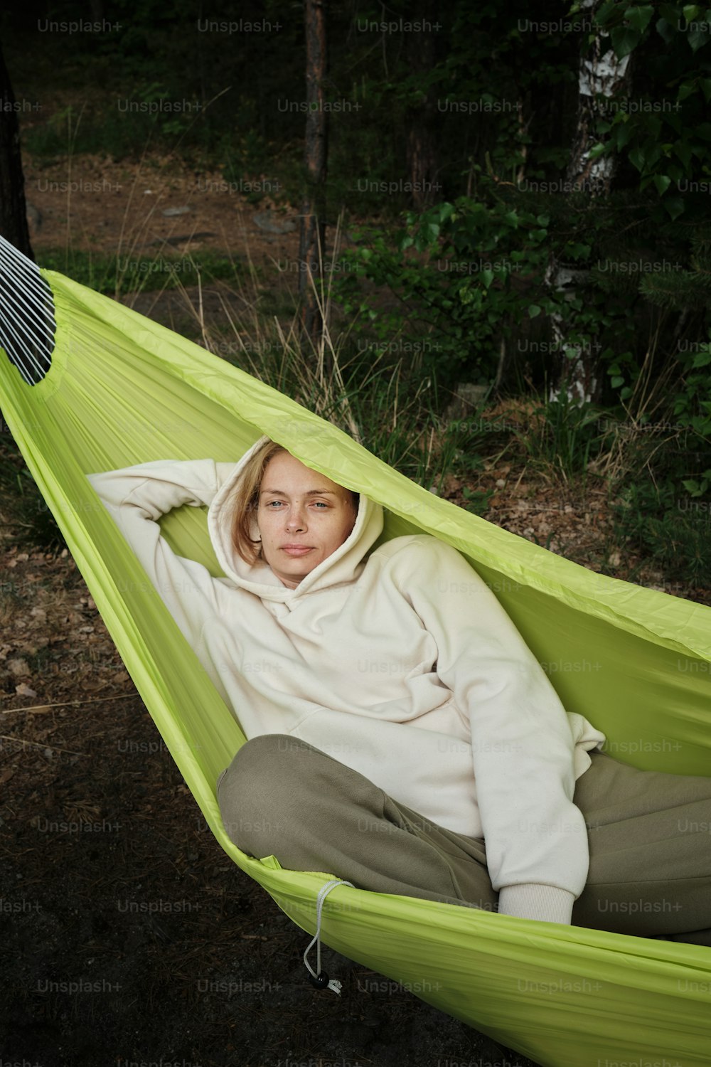 a woman sitting in a hammock in the woods