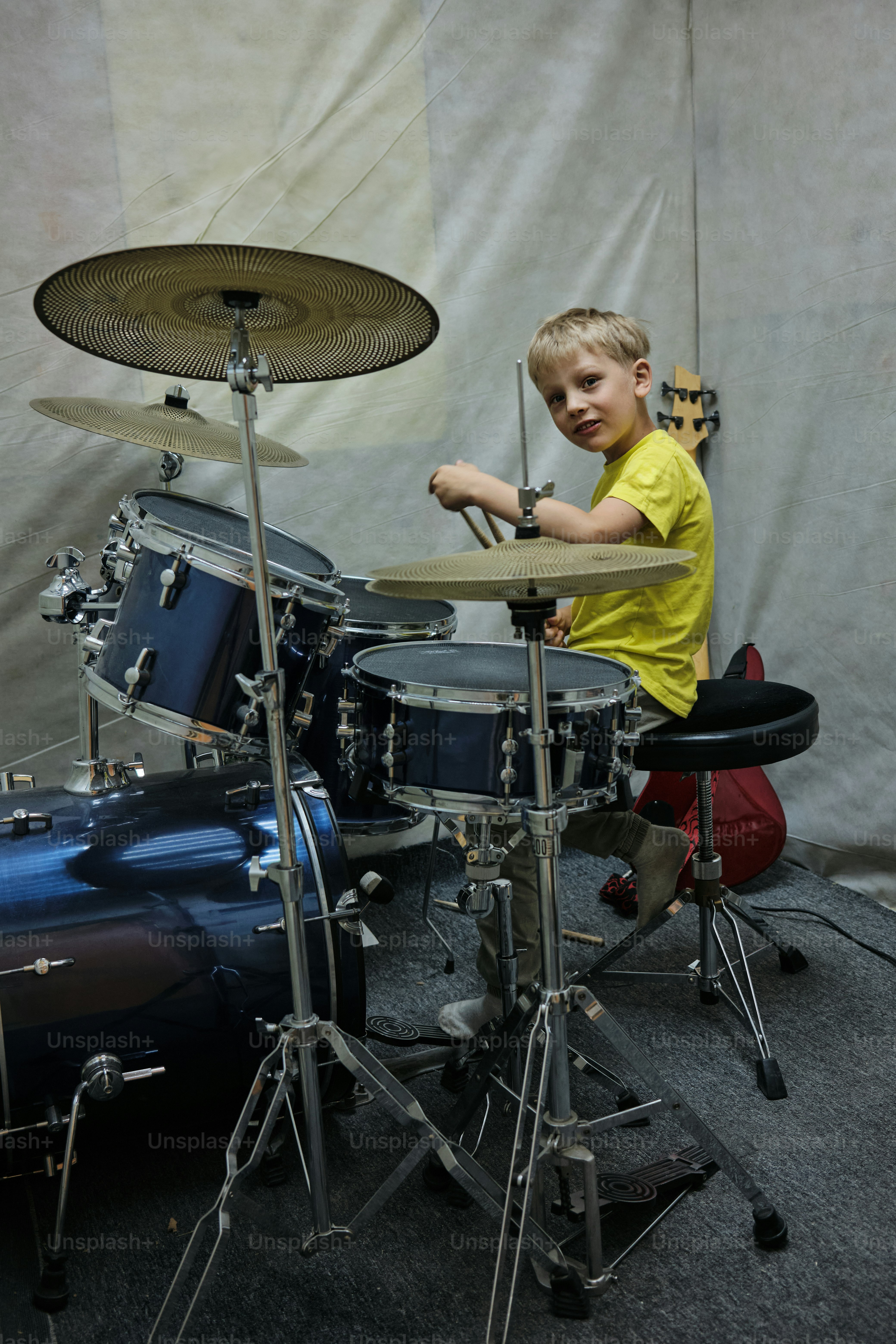 a young boy playing drums in front of a drum set