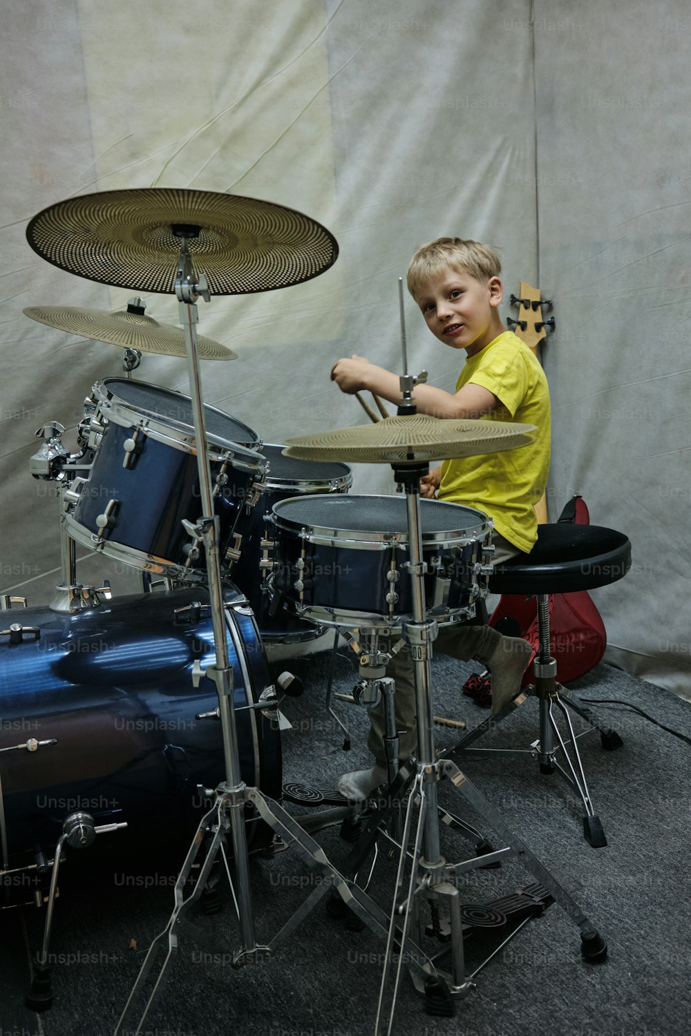 a young boy playing drums in front of a drum set