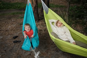 a boy and a girl laying in a hammock