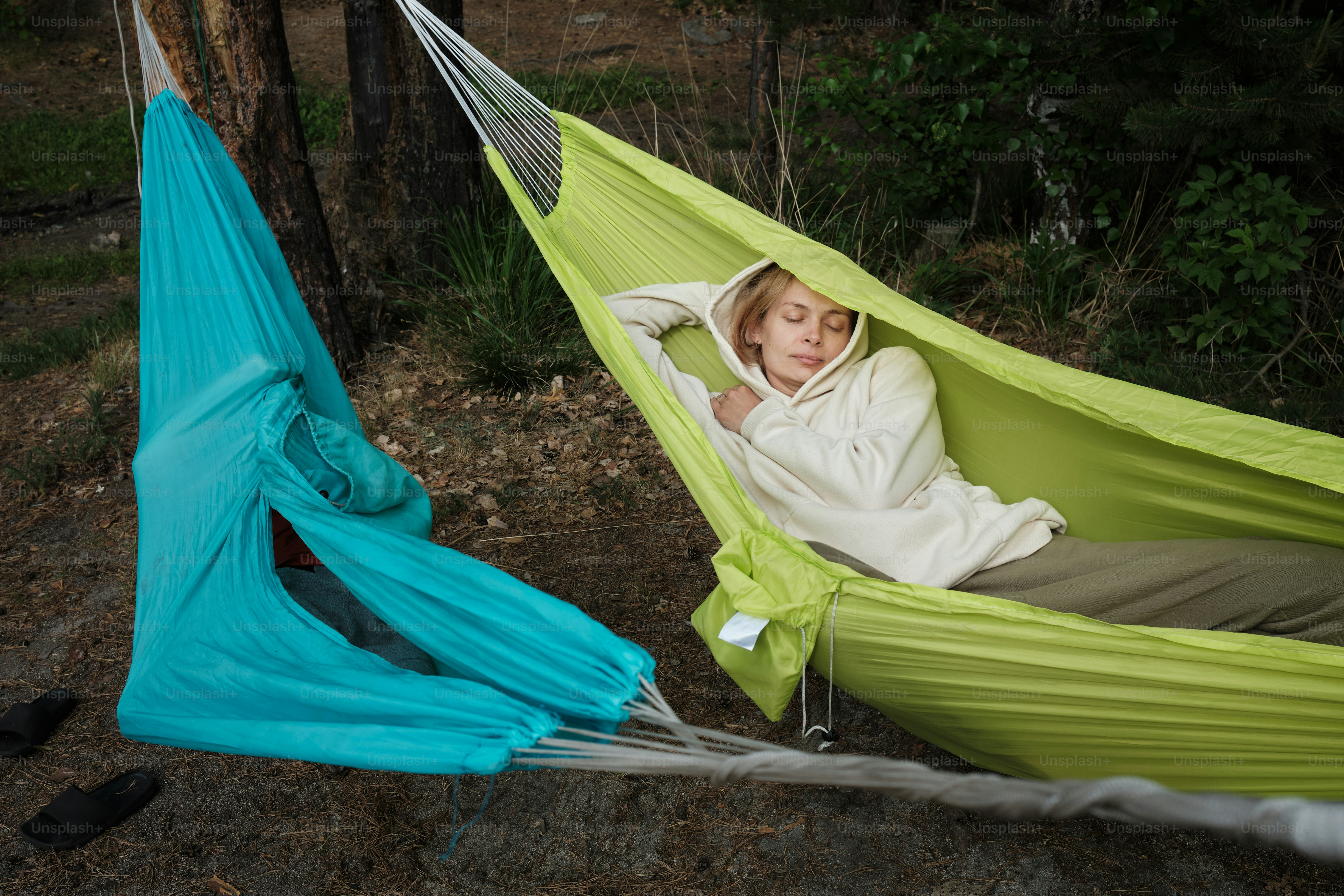 a woman laying in a hammock in a forest