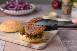 a hamburger being cut with a knife on a cutting board