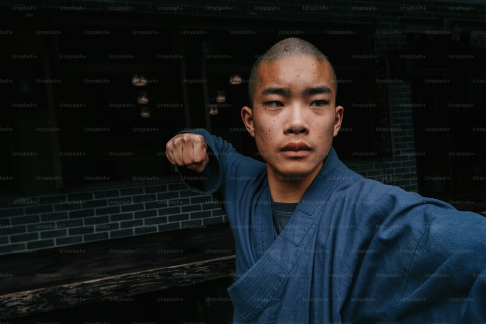 Um homem em um quimono azul posa para uma foto