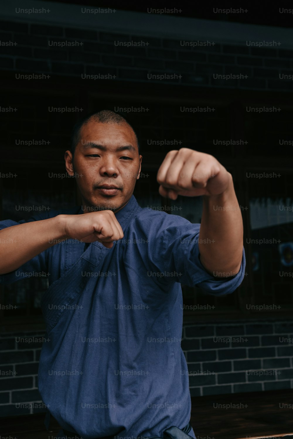Un hombre con una camisa azul flexionando sus músculos
